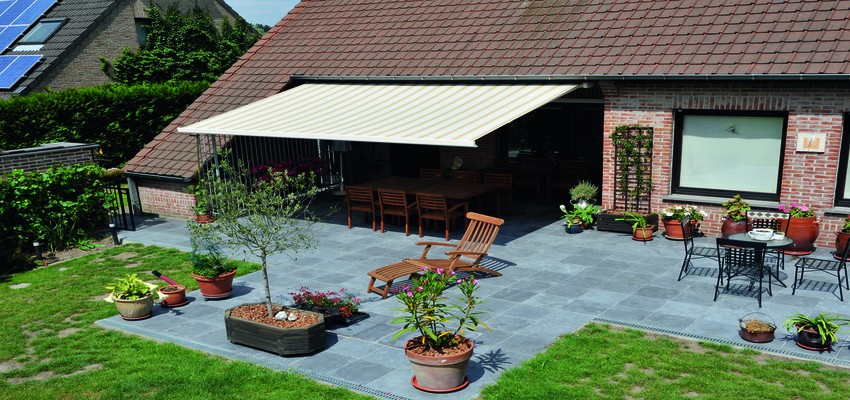 An awning attached to a house providing shade over patio furniture 